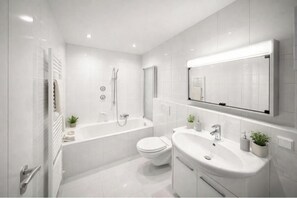 Ein modernes Badezimmer mit Badewanne, Toilette und Waschbecken, alles in Weiß.