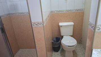 Un baño con inodoro, un cubo de basura y azulejos con diseño.