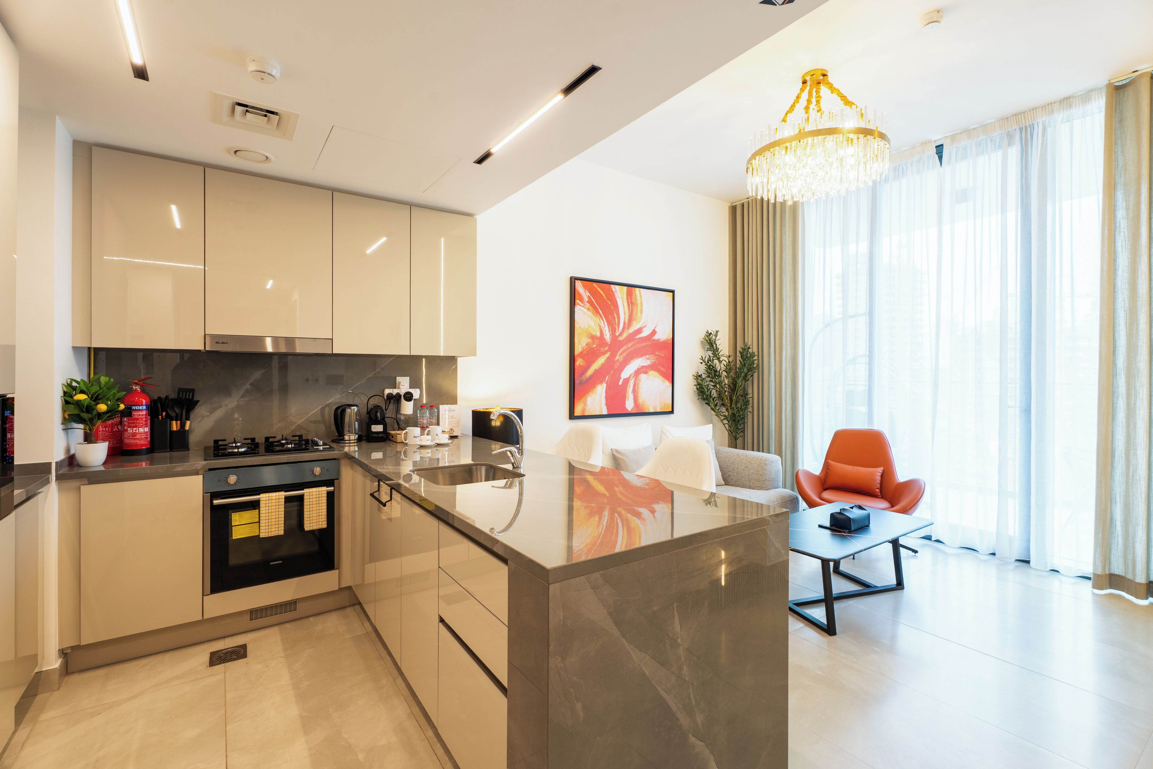 A modern kitchen with a central island, stainless steel appliances, and a dining area with a table and chairs.