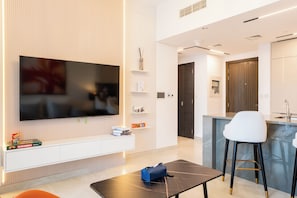 A modern living room with a flat-screen TV, a coffee table, a bar area, and a seating space. - Rentico Lux 1BR Burj View Paragon (Dubai)