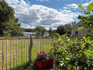 A fenced garden with a wooden house in the background. - Farmhouse with tiled stoves near lake and forest (Asarum)