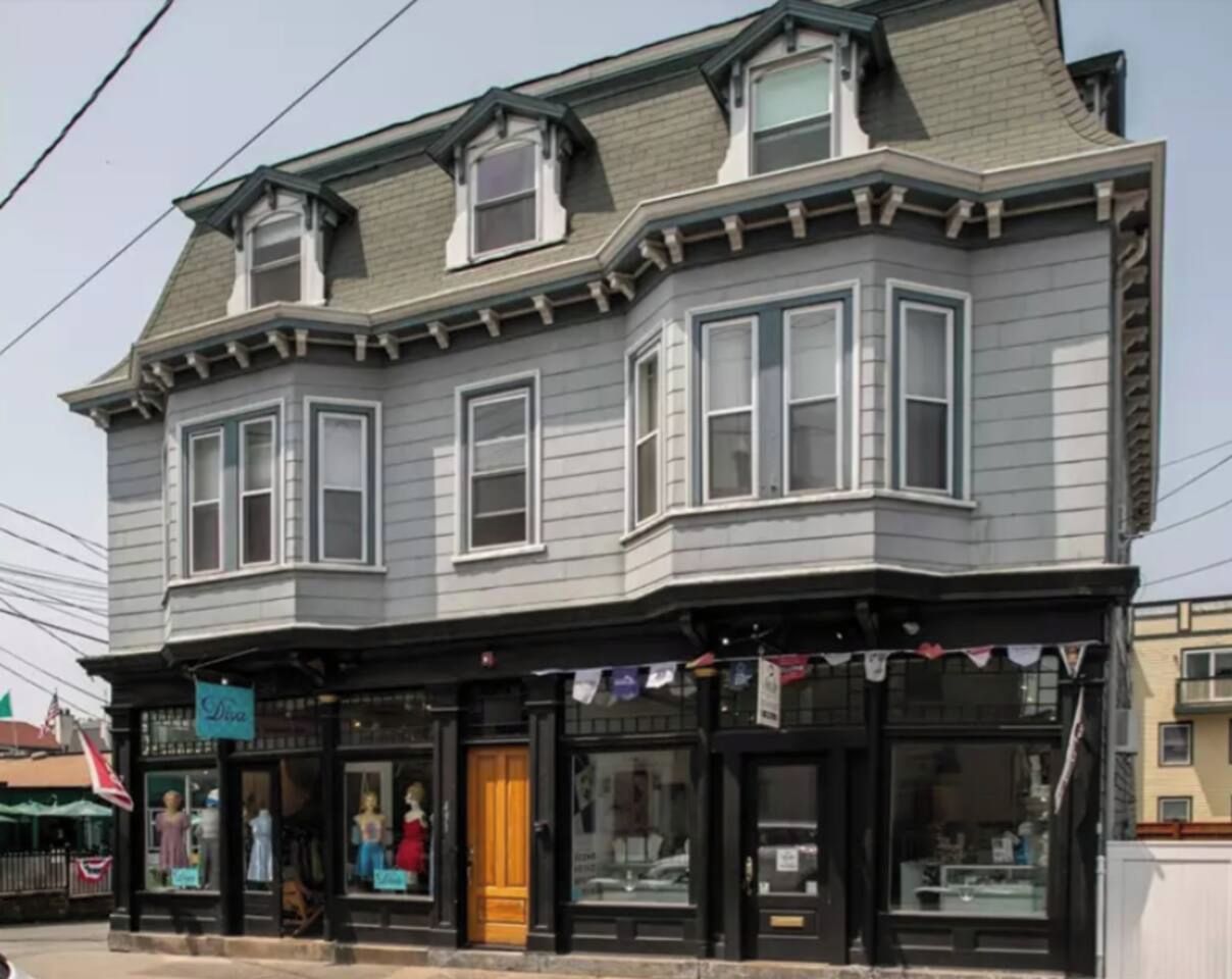 A two-story building with a corner entrance, large windows, and a storefront with a sign.