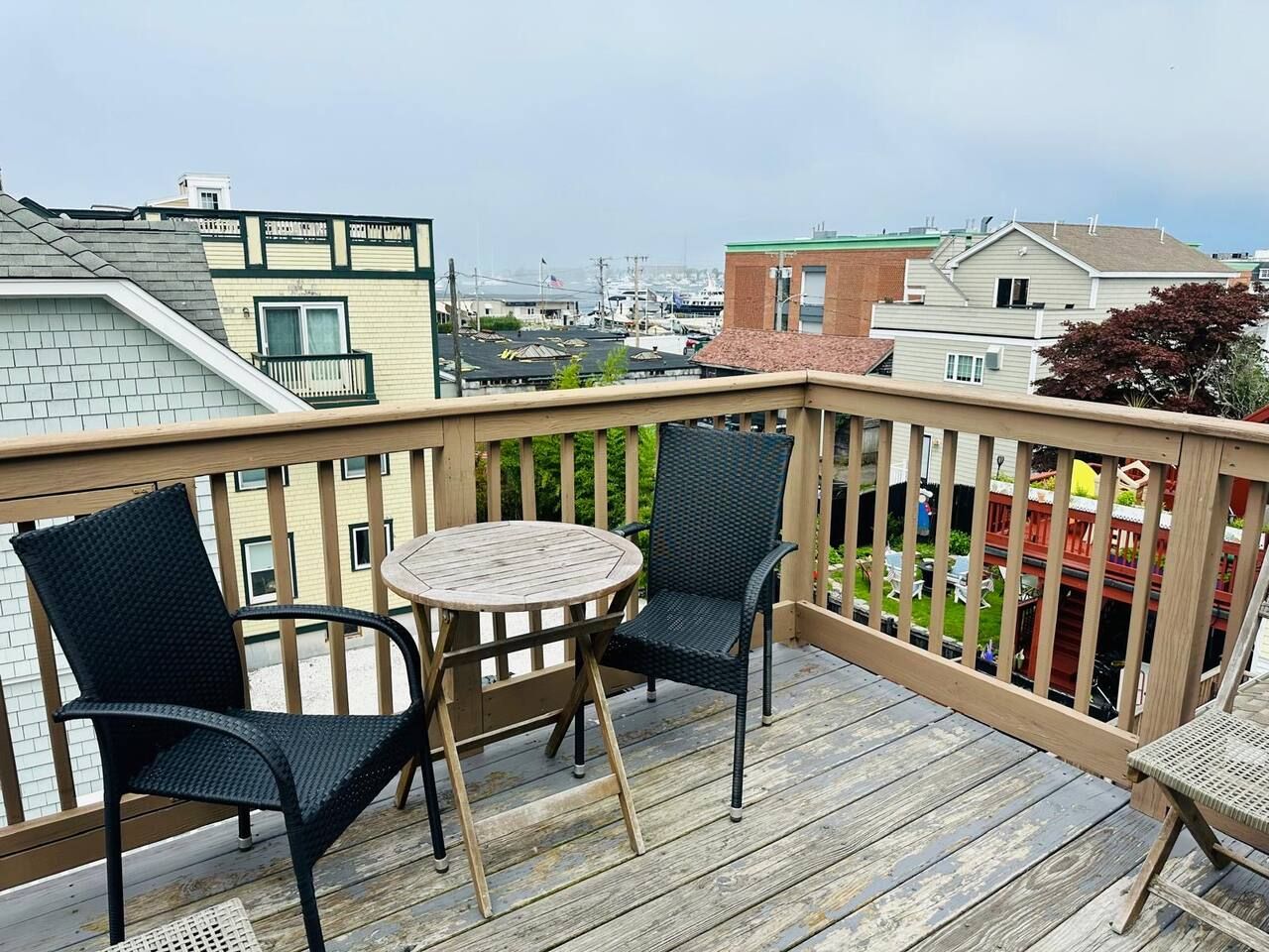 A wooden deck with two chairs and a table, overlooking a residential area.