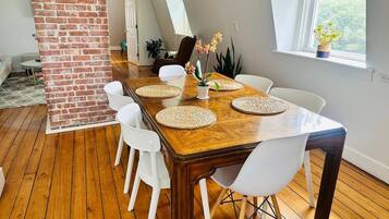 A dining area with a wooden table, white chairs, and woven placemats.
