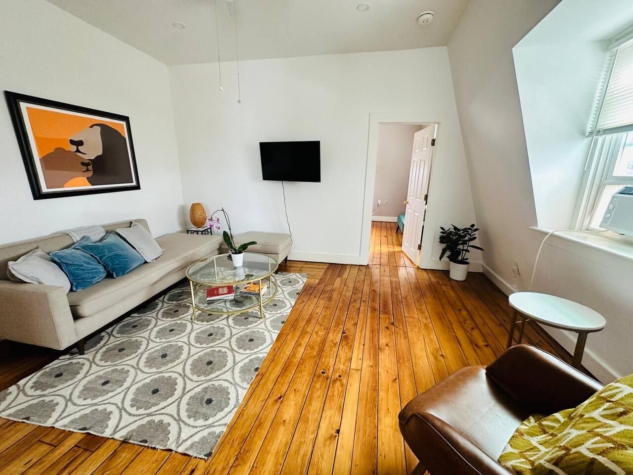 A modern living room with a sofa, coffee table, and a flat-screen TV mounted on the wall.