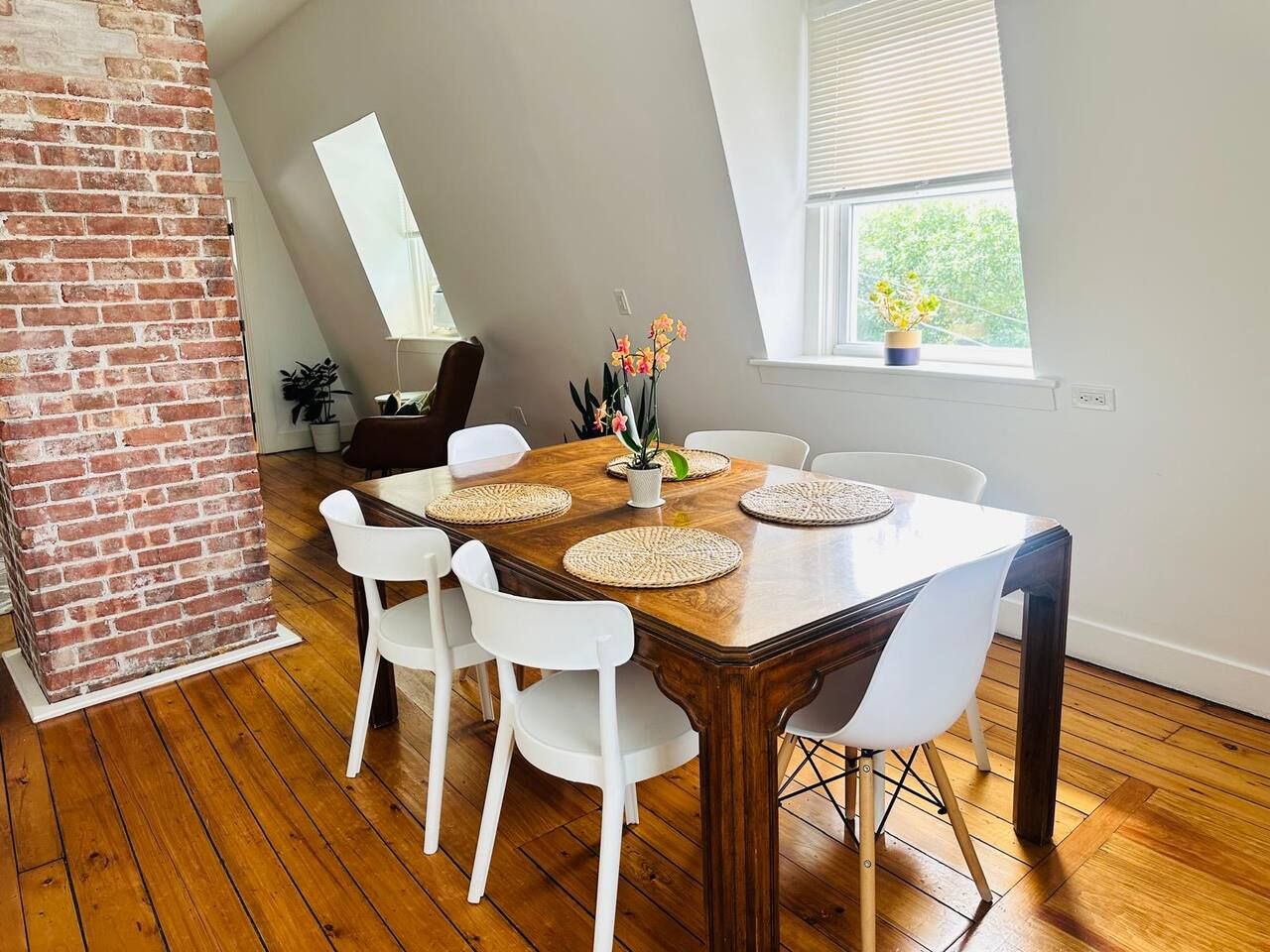 A dining area with a wooden table, white chairs, and a brick accent wall.