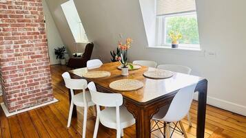 A dining area with a wooden table, white chairs, and a brick accent wall.