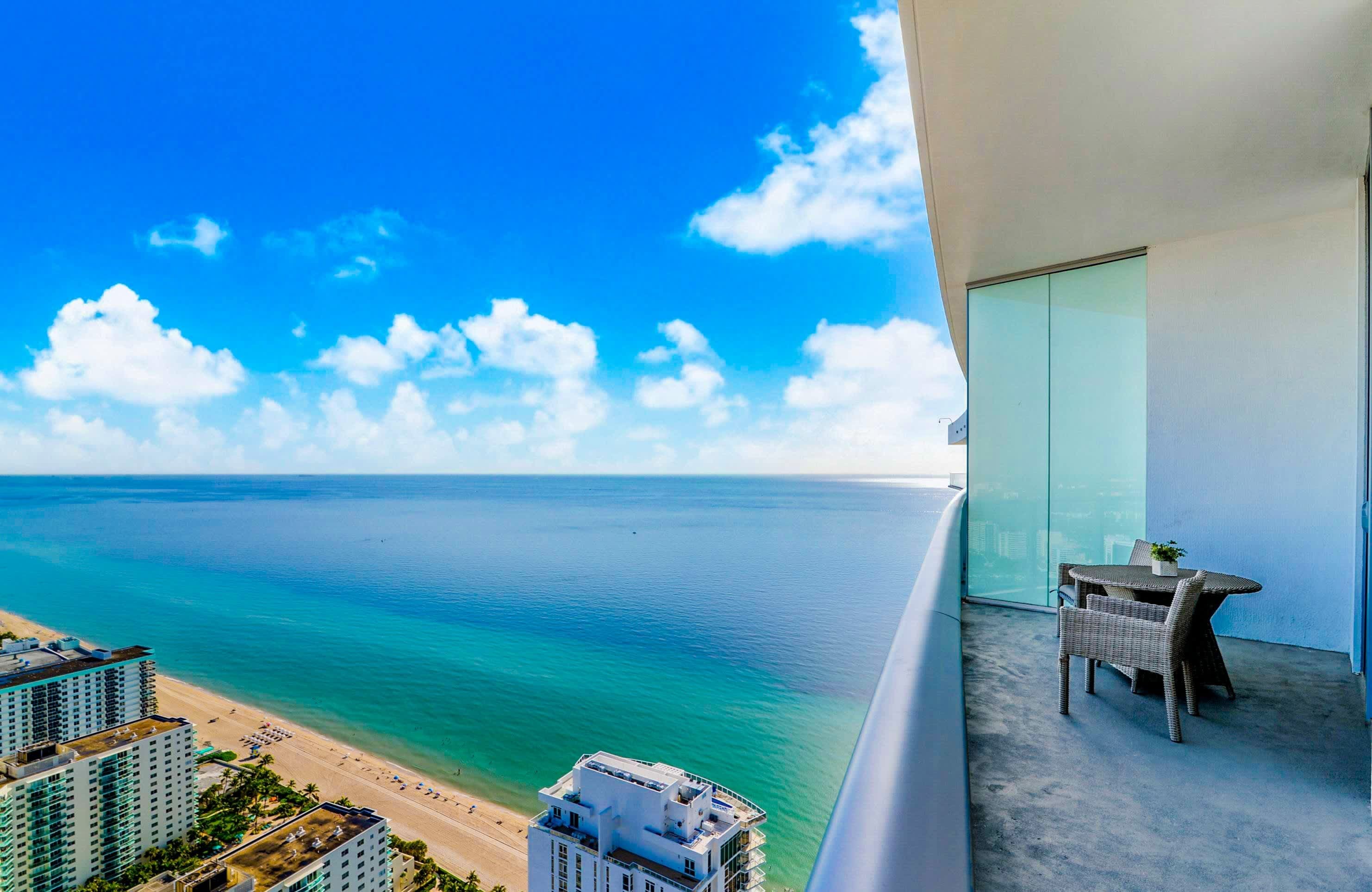 A balcony with a view of the ocean and a beach.