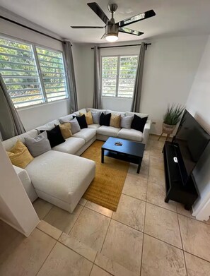 A modern living room with a sectional sofa, a coffee table, and a television. - El Yunque Sunset Mountain Villa • Private Pool (Canóvanas)