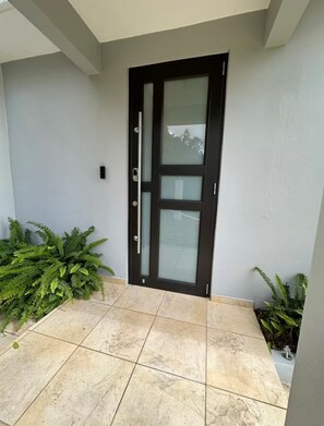 A modern door with glass panels, a metal handle, and a keyhole. - El Yunque Sunset Mountain Villa • Private Pool (Canóvanas)