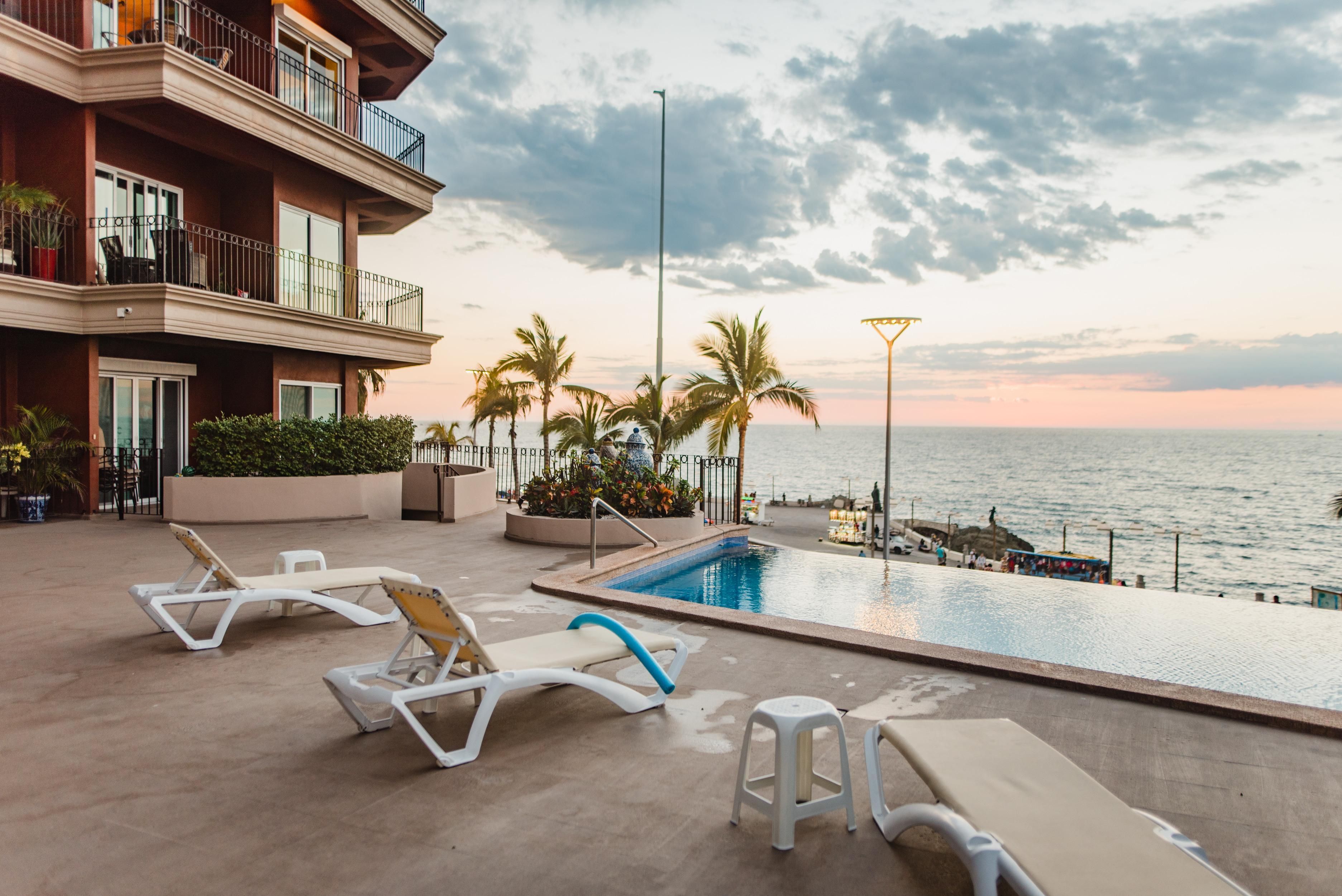 Un espace piscine avec des chaises longues et vue sur la mer.