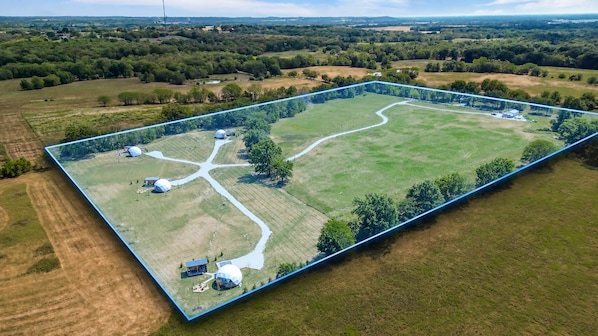 An aerial view of a large, rectangular property with multiple buildings, roads, and green fields.