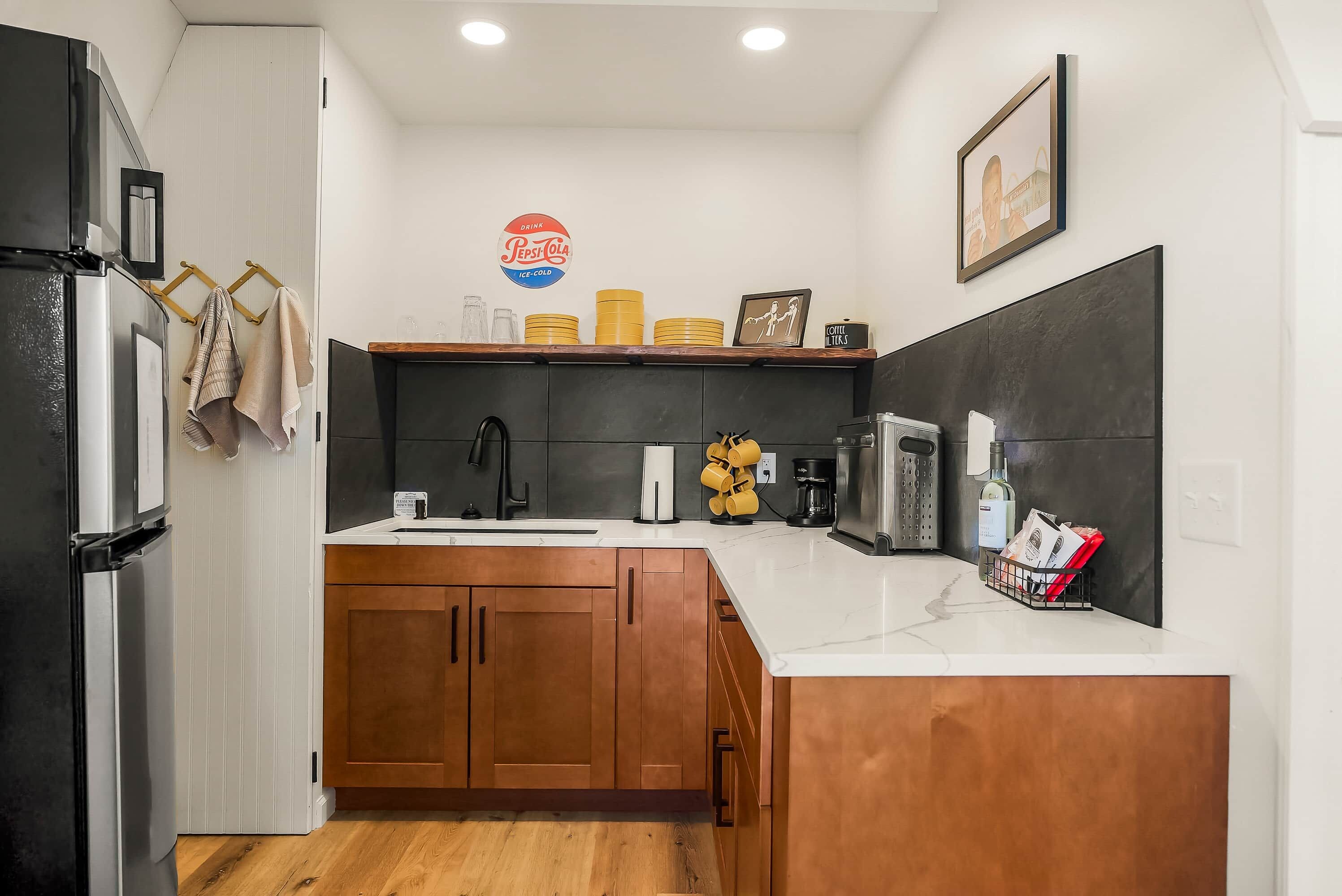 A kitchen with a refrigerator, stove, sink, and wooden cabinets.