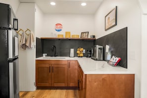 A kitchen with a refrigerator, stove, sink, and wooden cabinets.