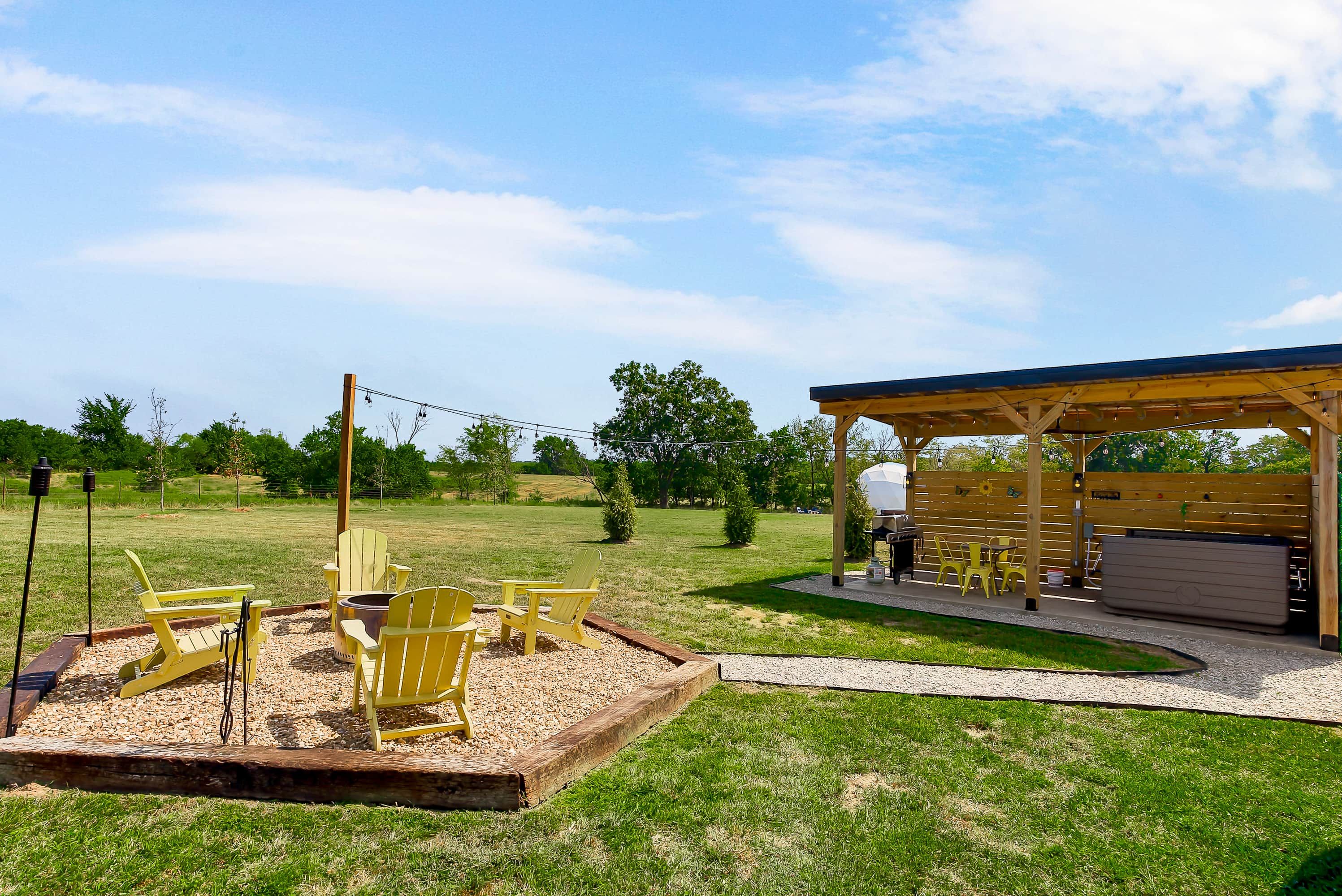 An outdoor seating area with Adirondack chairs, a barbecue grill, and a covered pavilion.
