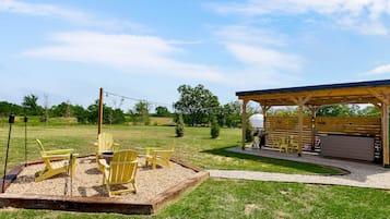 An outdoor seating area with Adirondack chairs, a barbecue grill, and a covered pavilion.