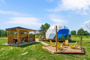 A wooden pavilion with outdoor seating and a geodesic dome structure.