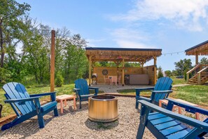 A wooden deck with outdoor seating, a fire pit, and a covered area with tables and chairs.