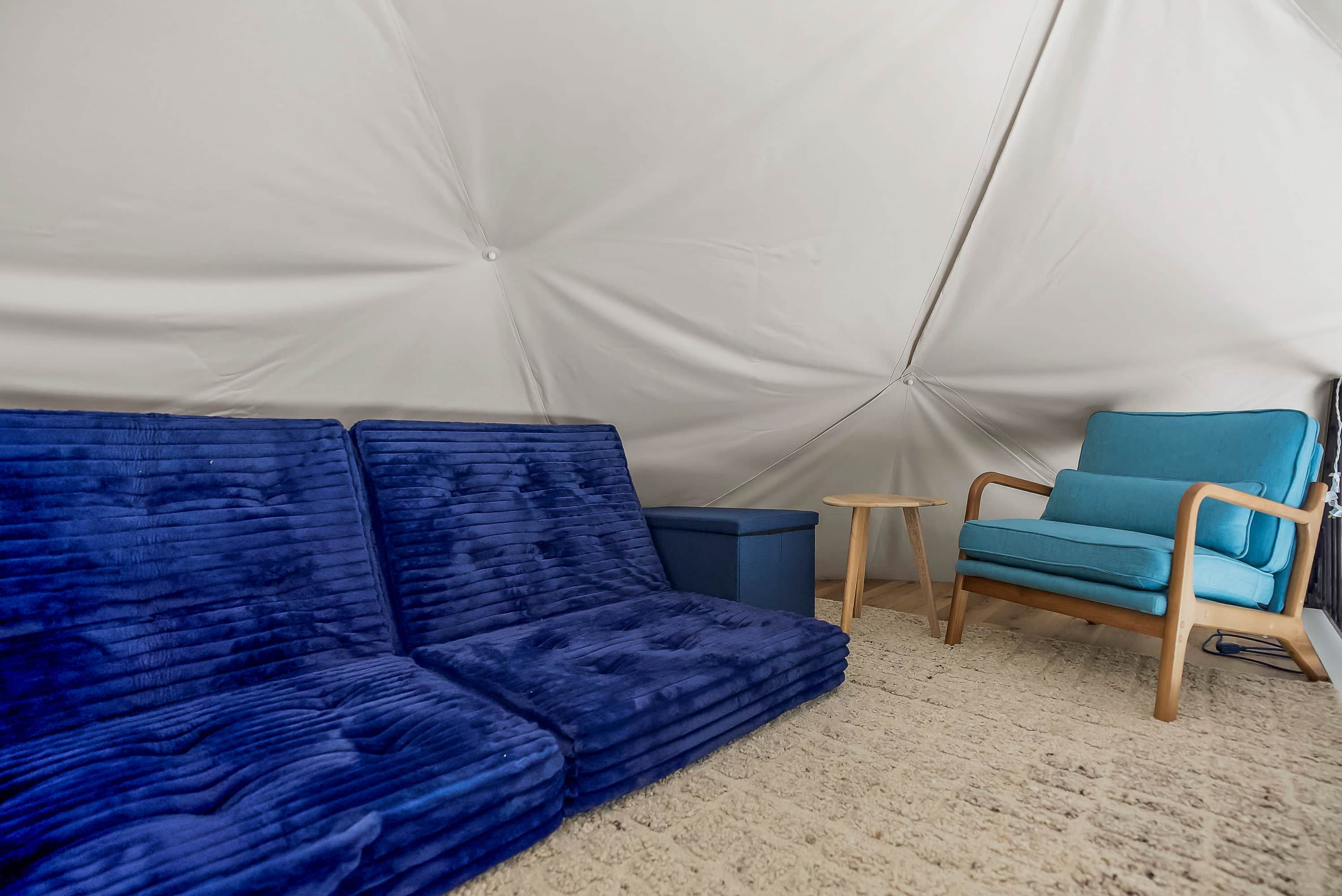 Een tent met een blauwe bank en een blauwe stoel binnen.