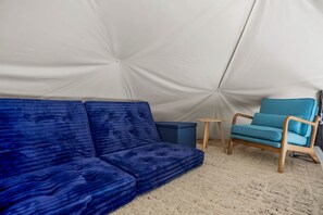 Ein Zelt mit einem blauen Sofa und einem blauen Sessel im Inneren.
