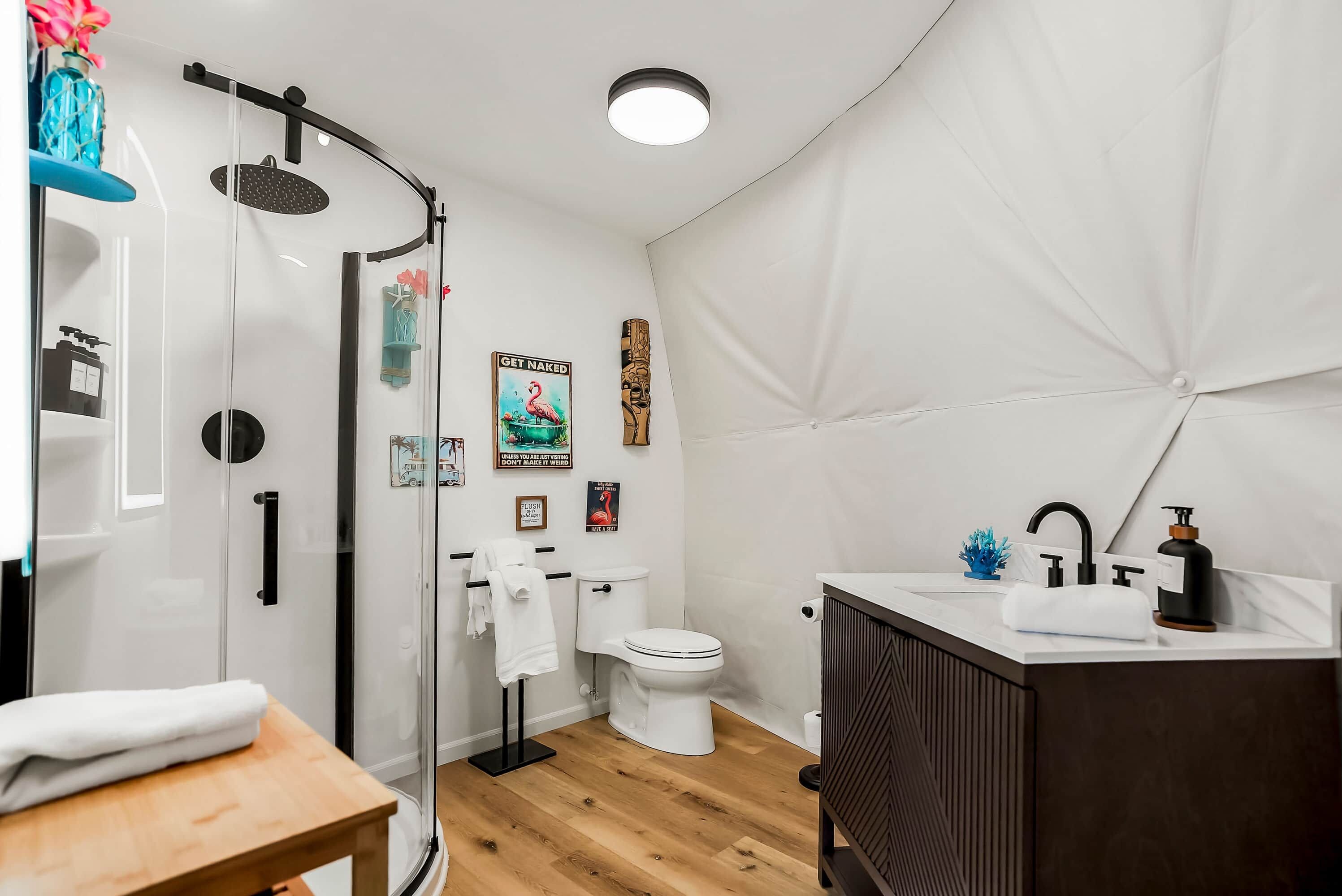 A modern bathroom with a glass shower enclosure, a toilet, and a sink area.