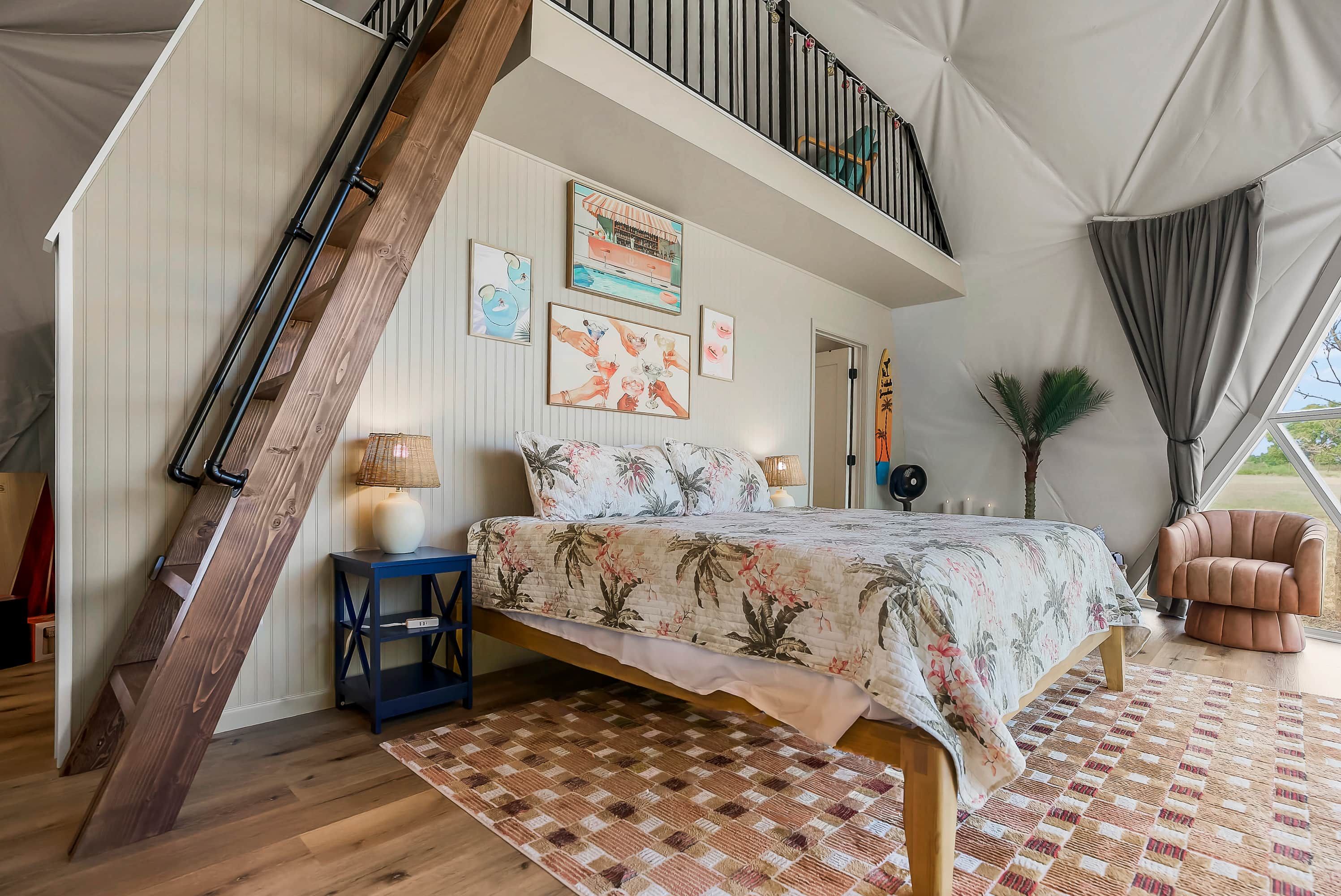 Een slaapkamer met een bed, nachtkastje, lamp, stoel en raam.
