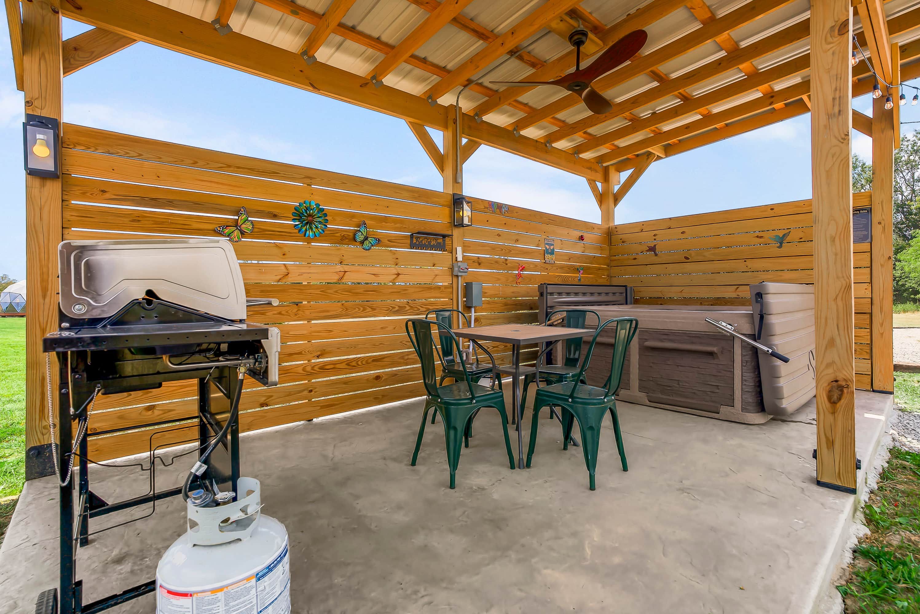 An outdoor patio with a grill, seating, and a gas cylinder.