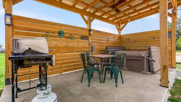 An outdoor patio with a grill, seating, and a gas cylinder.