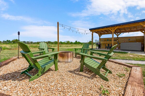 An outdoor seating area with Adirondack chairs and a fire pit, surrounded by gravel.