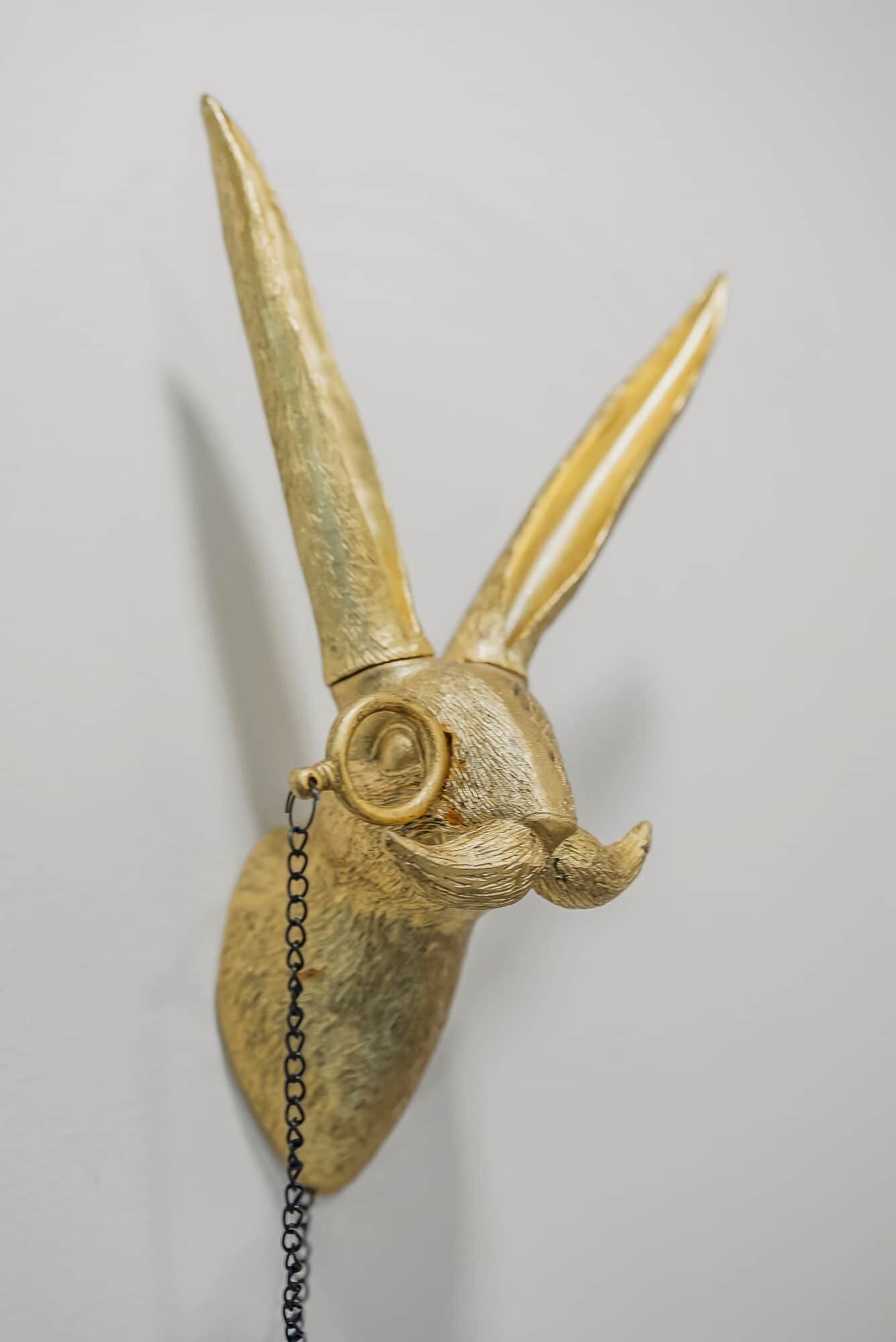 A gold-colored, textured object resembling a head with horns, attached to a chain.