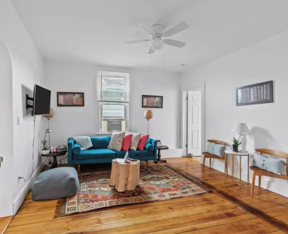 A living room with a blue sofa, a coffee table, and a ceiling fan.