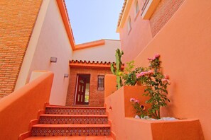 A narrow alleyway with a staircase leading to a door, a cactus, and a wall with a window. - CT 233 - 1001 Nights - 1001 Nights - CT 233 (Benalmadena)