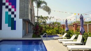 A swimming pool with lounge chairs and a colorful wall mural. - New Puerto Vallarta Calm Getaway , Pool & Garden (Parque Las Palmas)