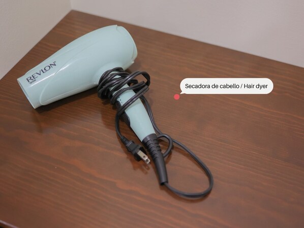 Un secador de pelo sobre una superficie de madera con un cable.