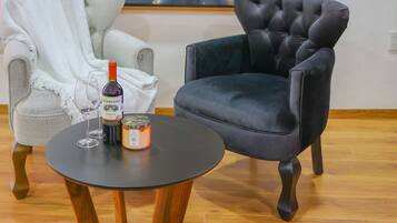 A room with two chairs, a table, a bottle of wine, and a candle.