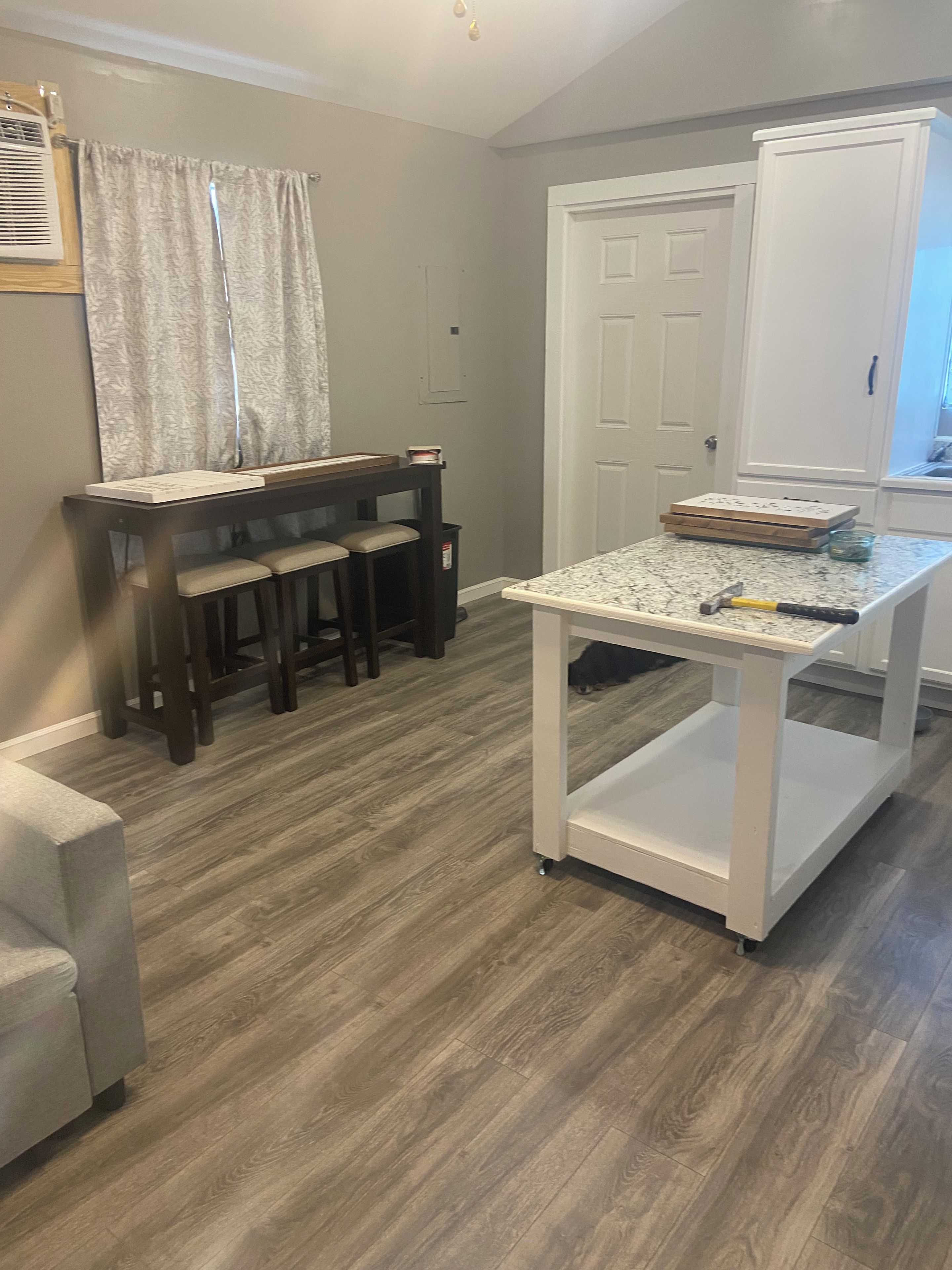 Una habitación con un piano, una mesita con un martillo y una puerta.