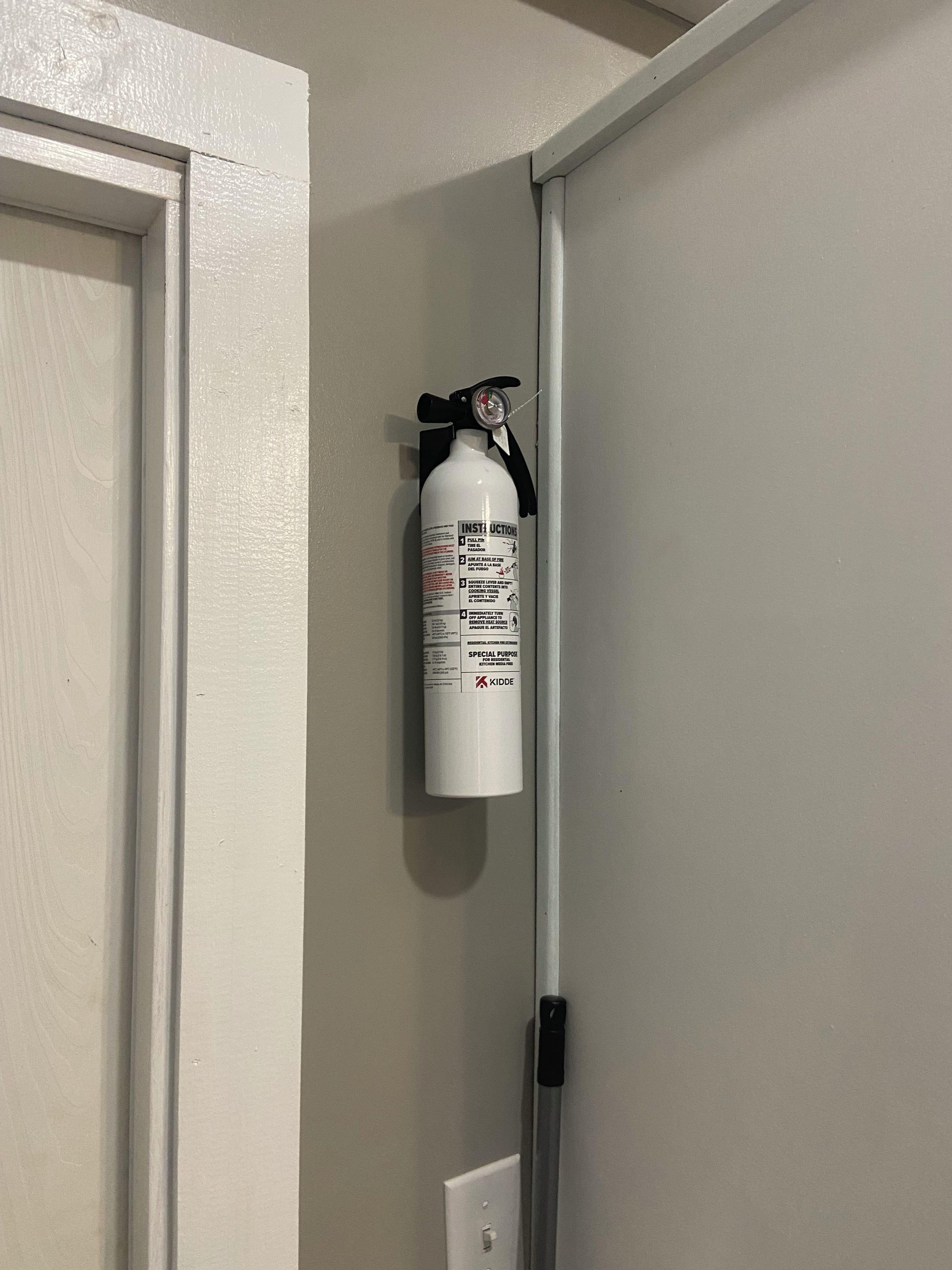 Un extincteur rouge fixé au mur, près d’une porte.