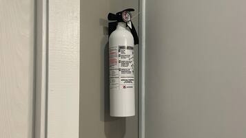Un extincteur rouge fixé au mur, près d’une porte.