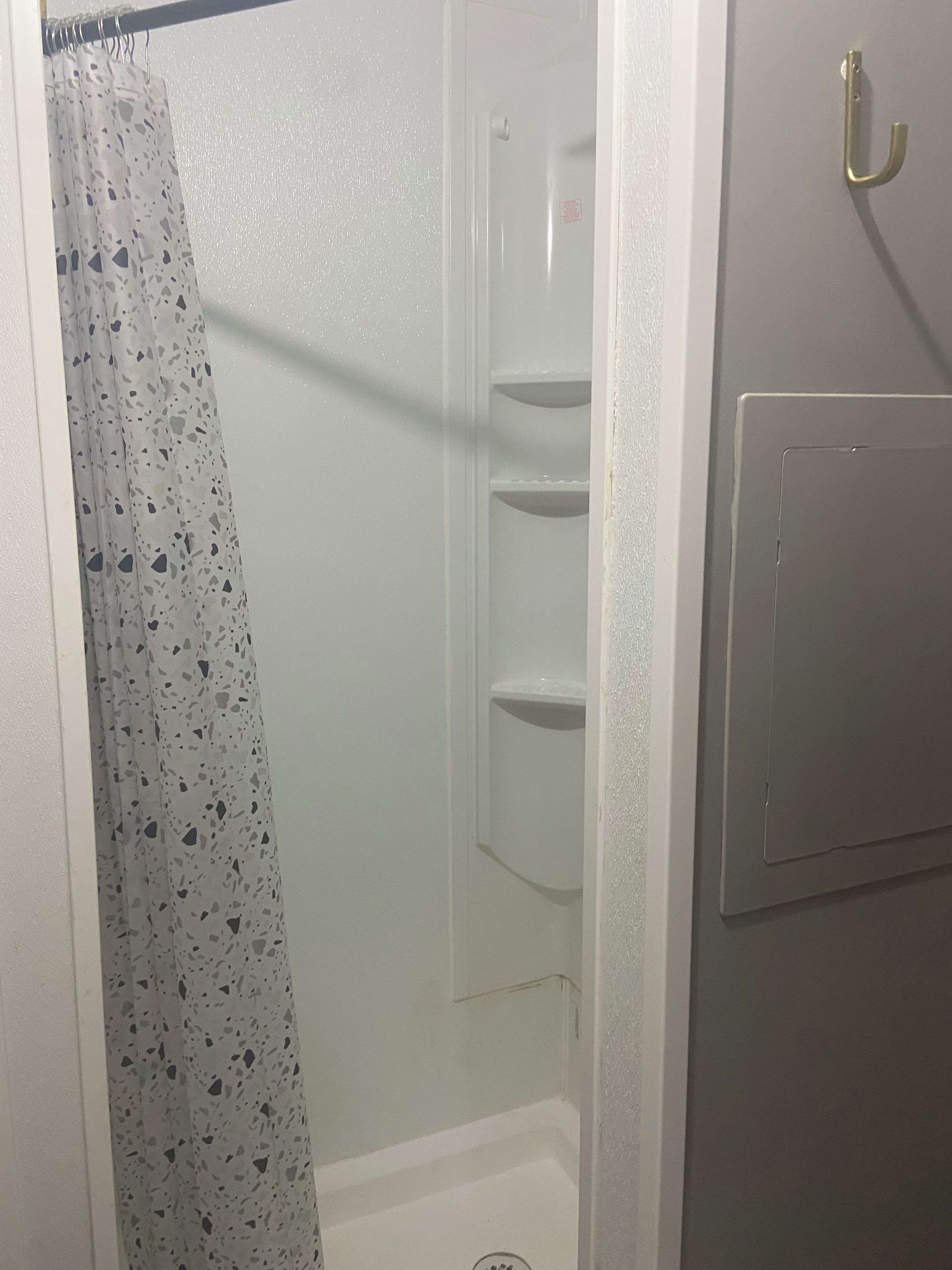 A bathroom with a shower curtain, a toilet, and a wall-mounted shelf.