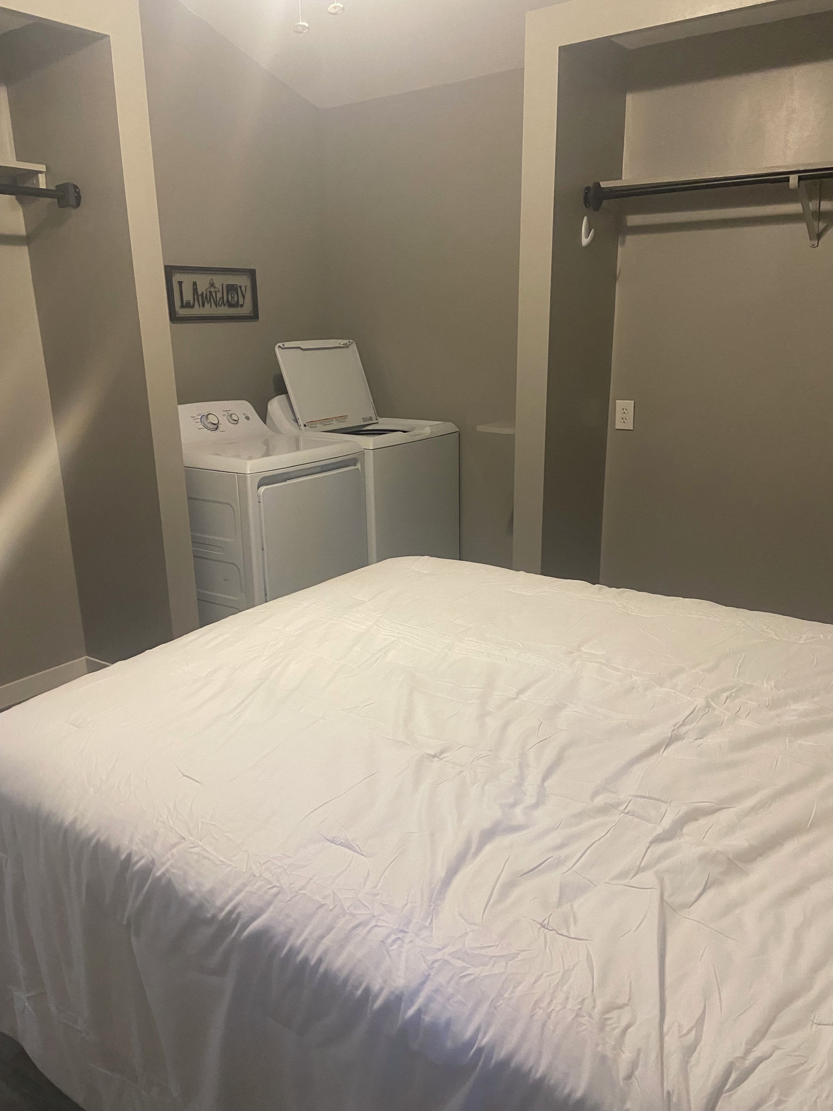 A bedroom with a bed, a washing machine, and a dryer.