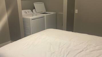 A bedroom with a bed, a washing machine, and a dryer.