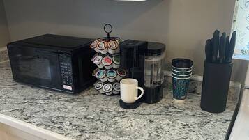 Une cuisine équipée d’un four à micro-ondes, d’une machine à café et de différents récipients posés sur le plan de travail.