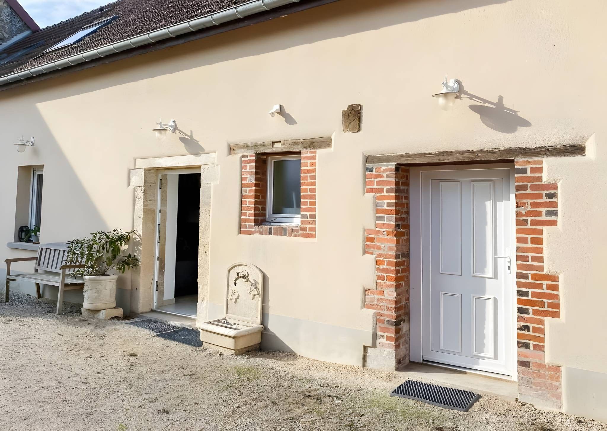 A building with a white door, a small window, and a bench outside.
