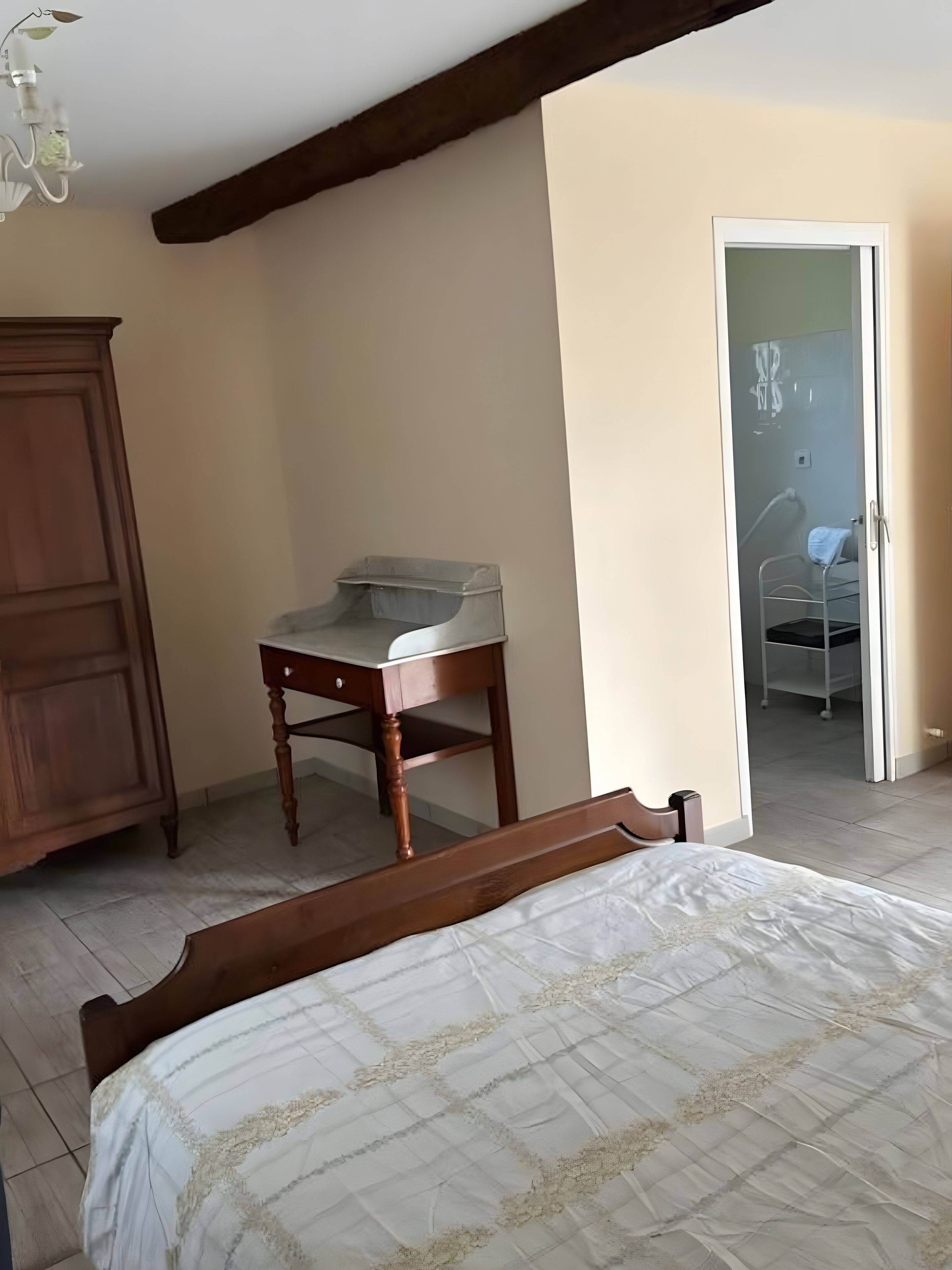 Une chambre à coucher avec un lit en bois, une table de chevet en bois, une petite table et une armoire.