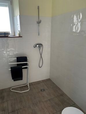 A bathroom with a shower, a towel rack, and a toilet.