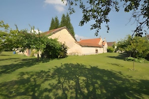 A house with a sloped roof, surrounded by a well-maintained lawn and trees.
