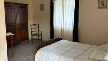 A bedroom with a bed, a wooden chair, a wardrobe, and a desk.