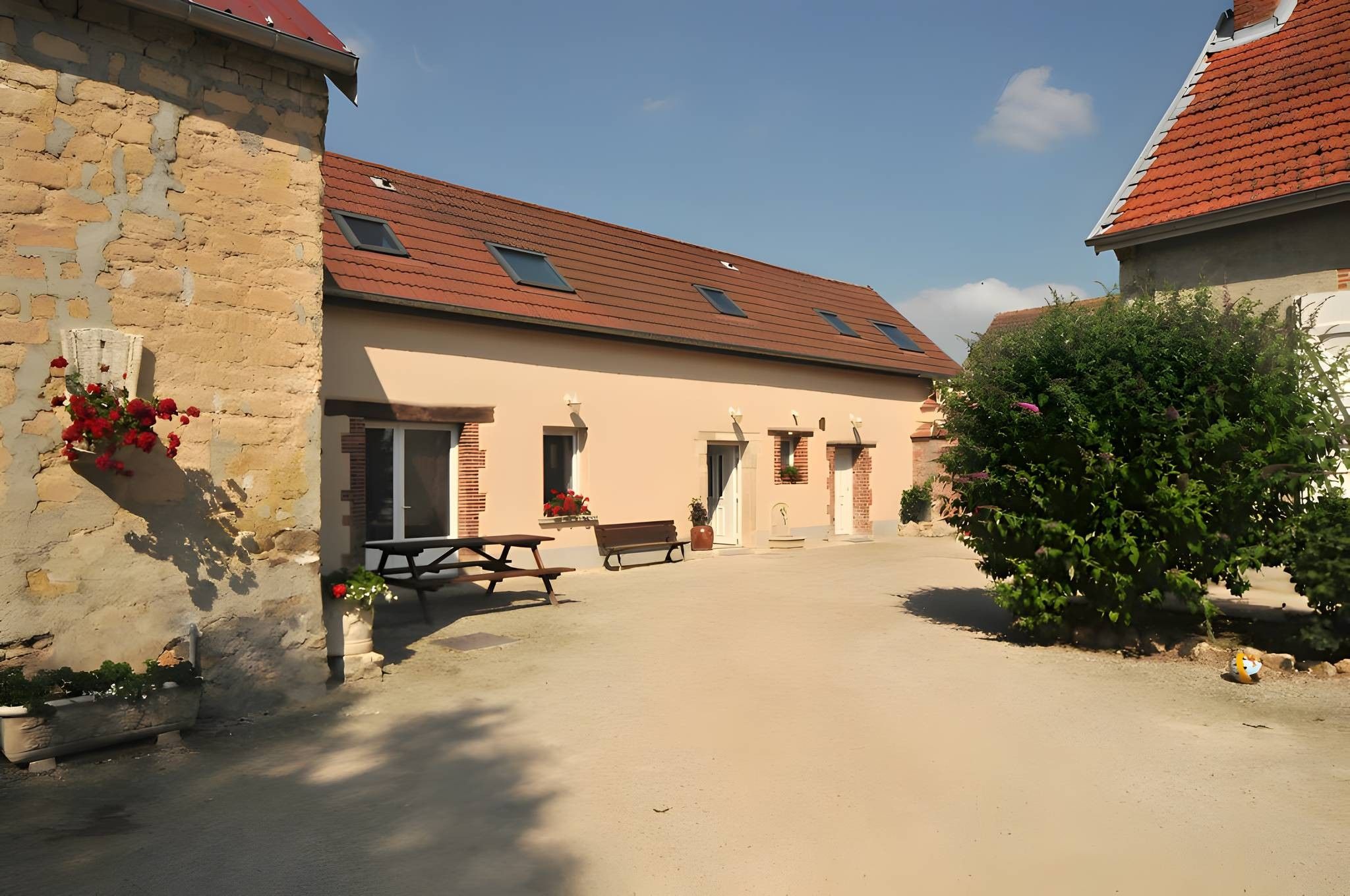 A courtyard with a building featuring a tiled roof and a bench.
