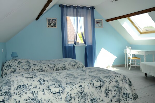 A bedroom with two beds, a desk, and a chair.