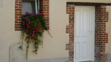 A building with a white door and a window with hanging flowers.